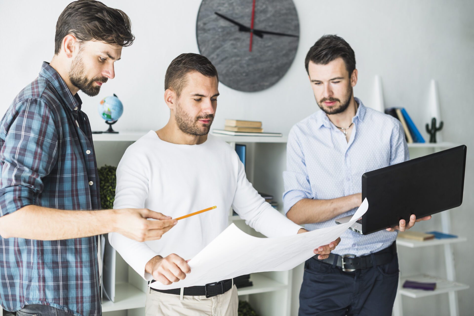 group-male-architect-using-laptop-while-looking-blueprint